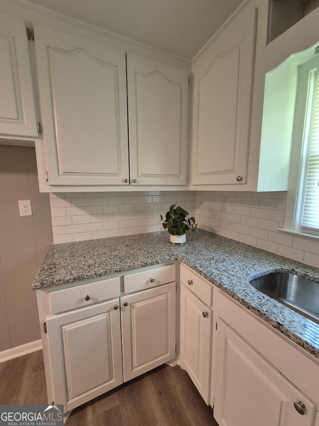 kitchen with backsplash, white cabinetry, light stone counters, and dark wood-style floors
