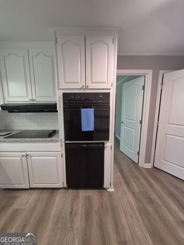 kitchen featuring light wood finished floors, decorative backsplash, black appliances, and under cabinet range hood