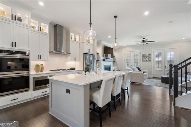 825 Maplewood Dr, Roswell, GA 30075 - kitchen featuring open floor plan, wall chimney range hood, ceiling fan, light countertops, and stainless steel appliances
