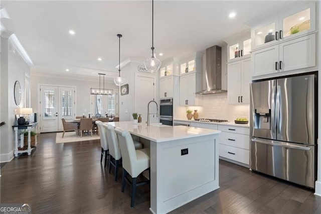 825 Maplewood Dr, Roswell, GA 30075 - kitchen featuring tasteful backsplash, light countertops, a kitchen island with sink, wall chimney exhaust hood, and appliances with stainless steel finishes