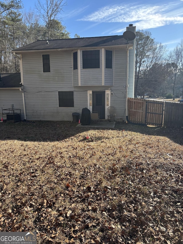 back of property with fence, central AC, and a chimney