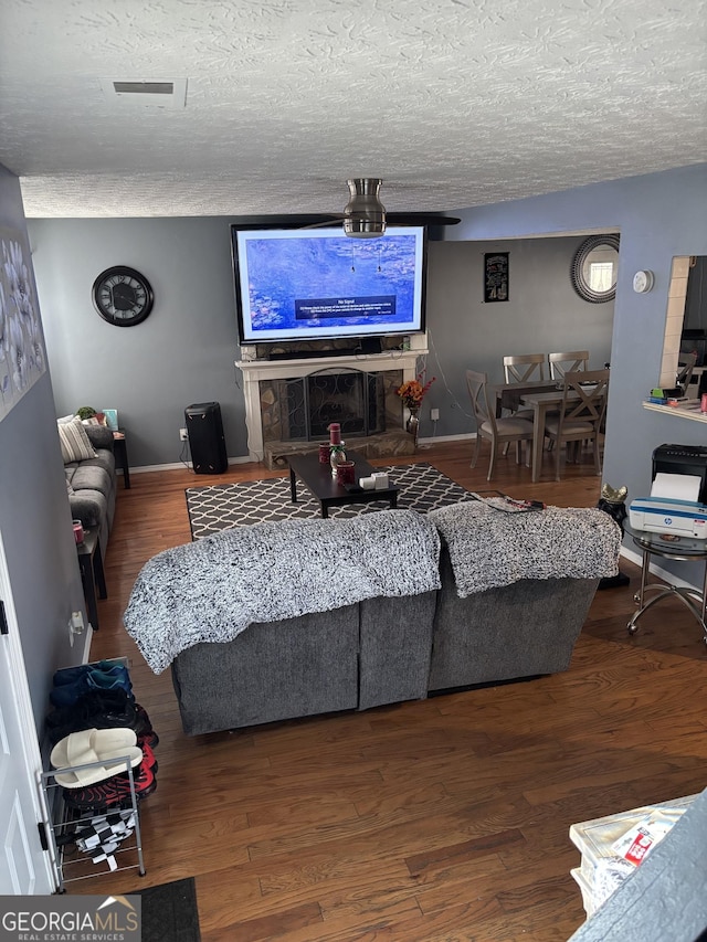 living area featuring visible vents, wood finished floors, and a textured ceiling
