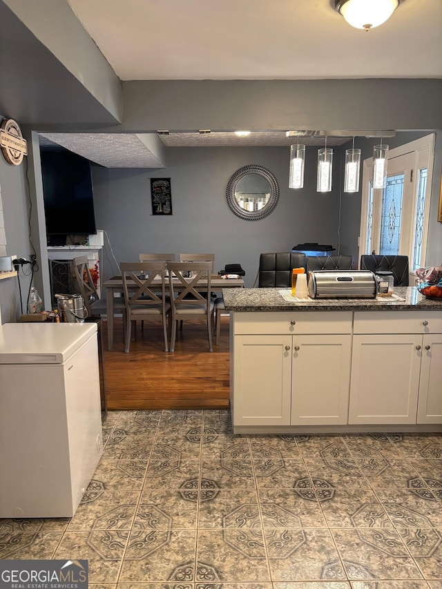 kitchen with white cabinets, dark tile patterned floors, open floor plan, and refrigerator