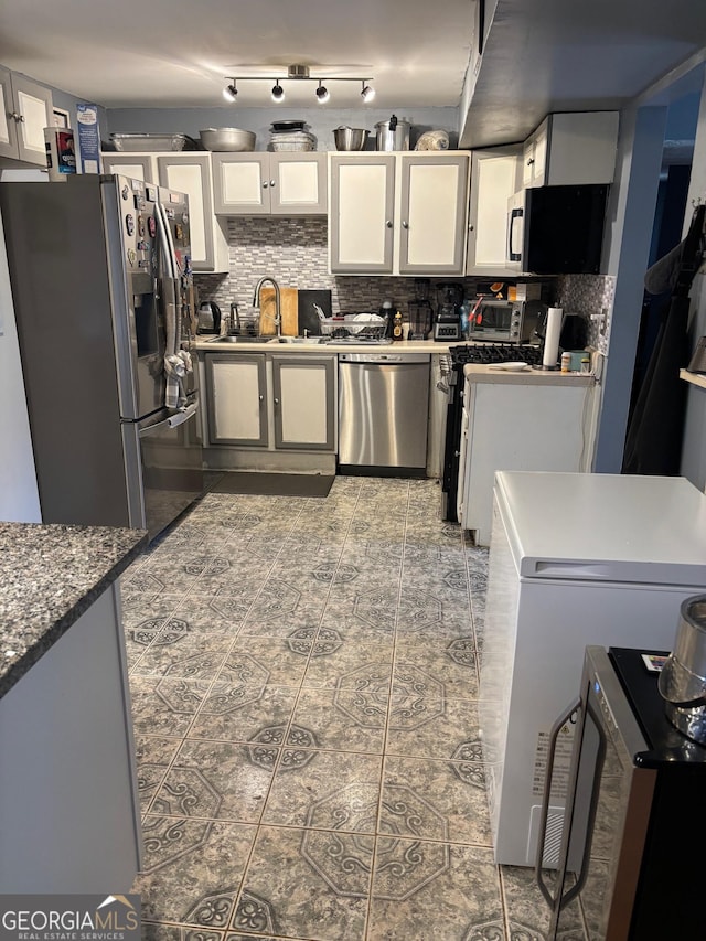 kitchen featuring a sink, decorative backsplash, appliances with stainless steel finishes, and white cabinetry