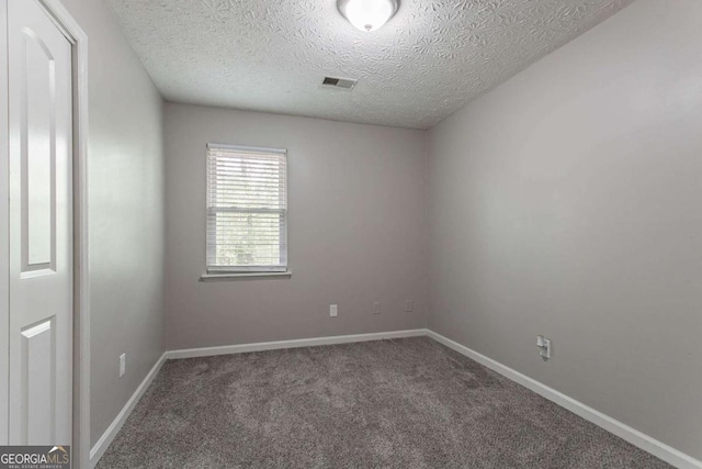 carpeted empty room with visible vents, baseboards, and a textured ceiling