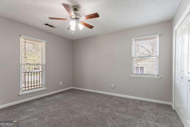 unfurnished bedroom featuring a closet, visible vents, multiple windows, and carpet