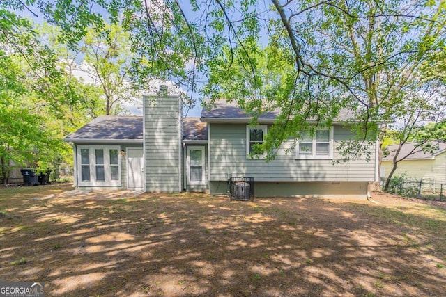 back of property with fence, a chimney, and a shingled roof