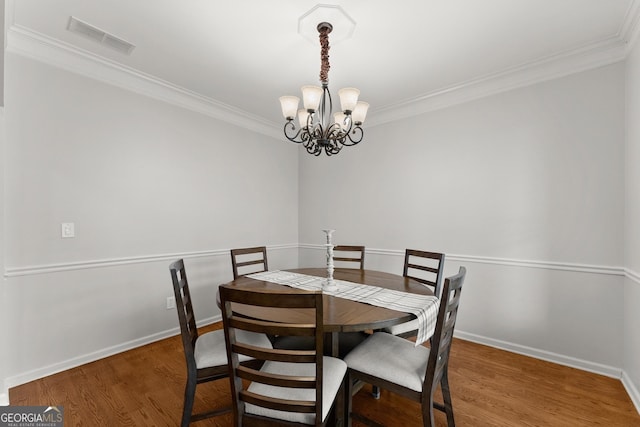 6058 Grand Reunion Dr, Hoschton, GA 30548 - dining room with a chandelier, visible vents, crown molding, and wood finished floors