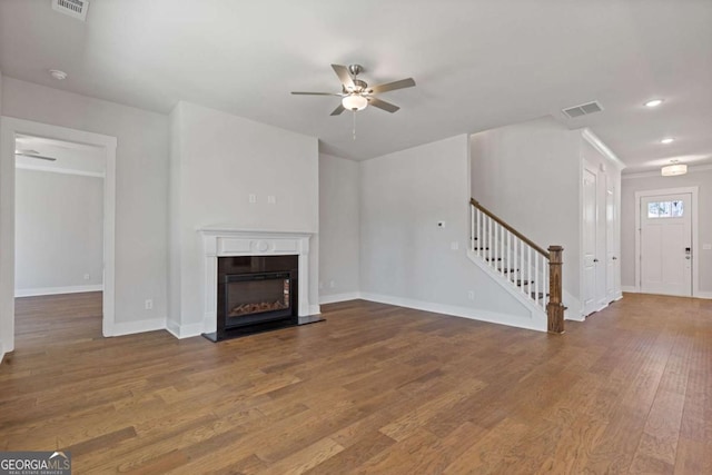 unfurnished living room with visible vents, baseboards, a ceiling fan, stairway, and wood finished floors