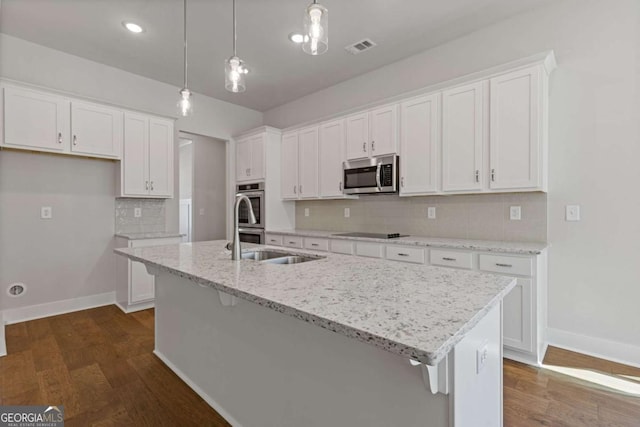 kitchen with dark wood-type flooring, visible vents, white cabinets, appliances with stainless steel finishes, and a kitchen island with sink