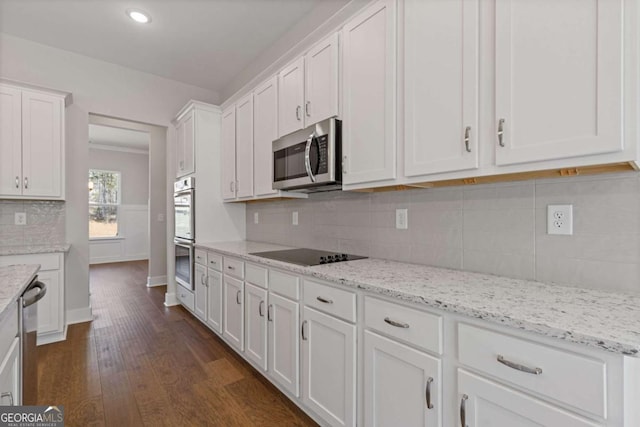 kitchen with light stone countertops, tasteful backsplash, white cabinetry, appliances with stainless steel finishes, and dark wood-style flooring