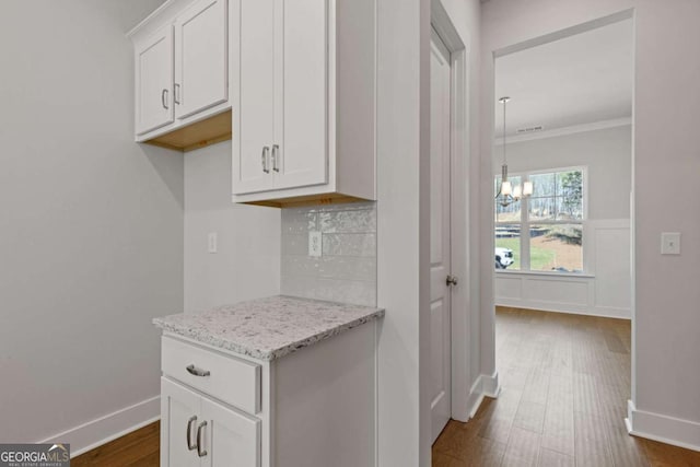 kitchen featuring tasteful backsplash, ornamental molding, a chandelier, dark wood-style floors, and white cabinetry