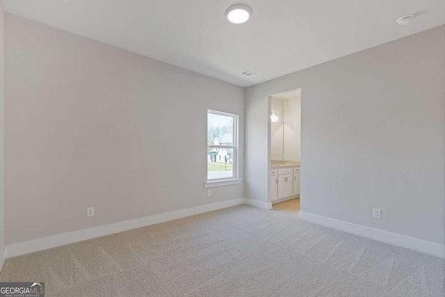 empty room with light carpet, visible vents, and baseboards