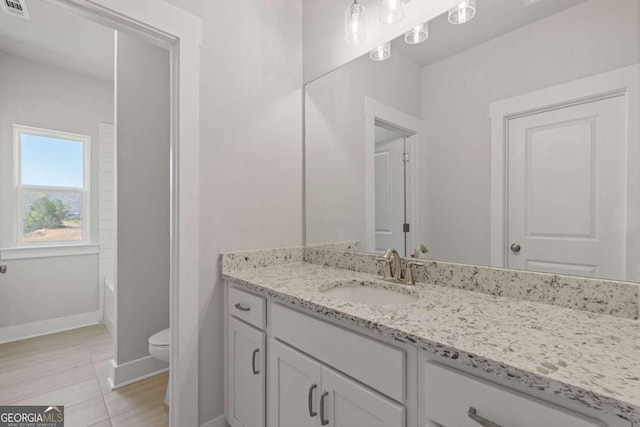 full bath featuring vanity, baseboards, a bathtub, toilet, and visible vents