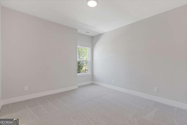 unfurnished room with visible vents, light colored carpet, and baseboards
