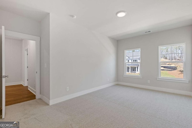 carpeted spare room with visible vents and baseboards