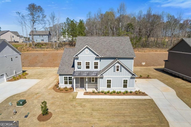 view of front of home with roof with shingles, driveway, board and batten siding, a front yard, and a porch