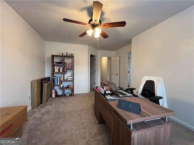 carpeted office with baseboards and a ceiling fan