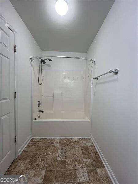 bathroom with bathtub / shower combination and baseboards