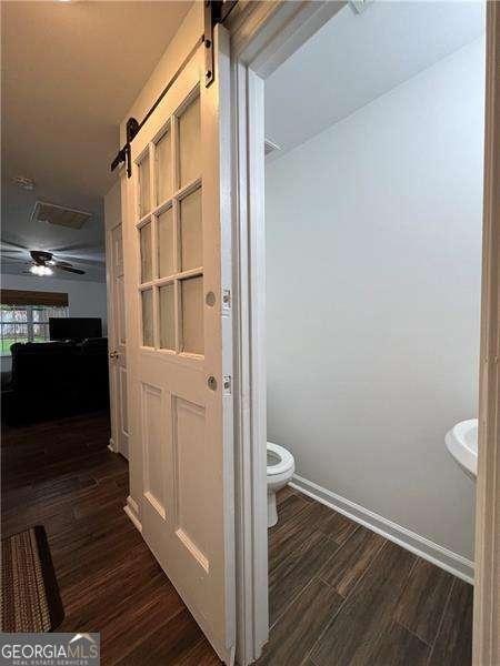 bathroom with baseboards, a ceiling fan, toilet, and wood finished floors