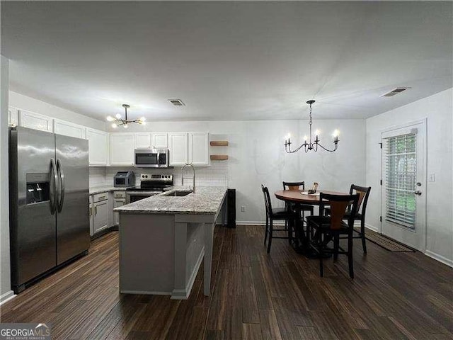 kitchen featuring a sink, dark wood-style flooring, appliances with stainless steel finishes, a chandelier, and a peninsula