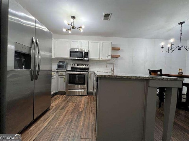 kitchen with a sink, visible vents, appliances with stainless steel finishes, and a notable chandelier