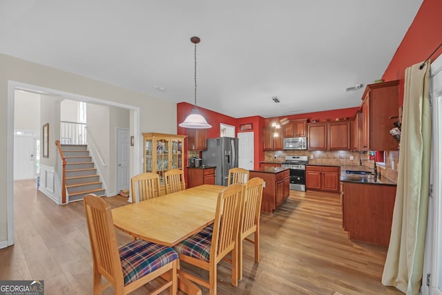 dining room with light wood-style floors, visible vents, and stairs