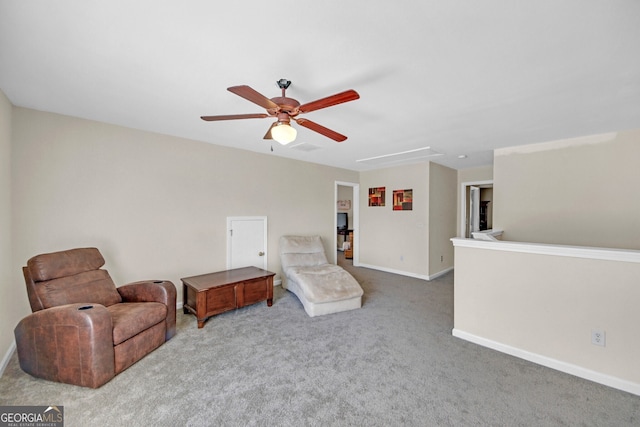 sitting room featuring baseboards, attic access, ceiling fan, and carpet
