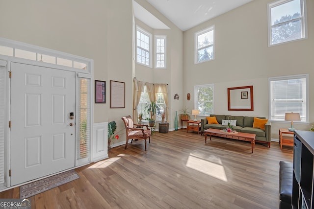 entrance foyer featuring baseboards, light wood-type flooring, and a high ceiling
