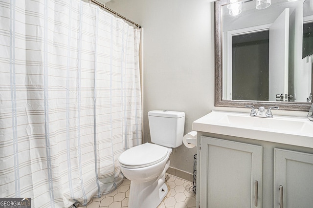 full bath featuring toilet, vanity, and baseboards