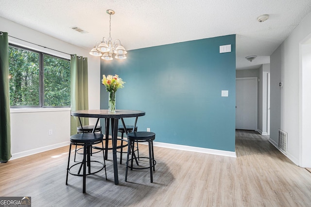 dining room with wood finished floors, a chandelier, baseboards, and a textured ceiling