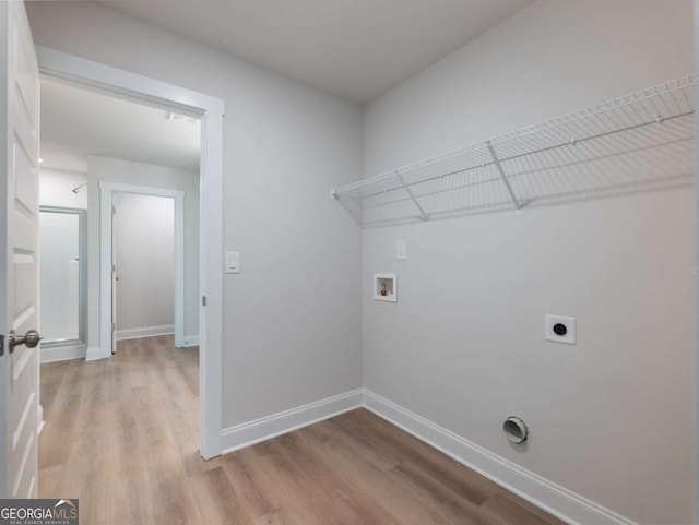 laundry area with hookup for an electric dryer, baseboards, light wood-style flooring, laundry area, and hookup for a washing machine