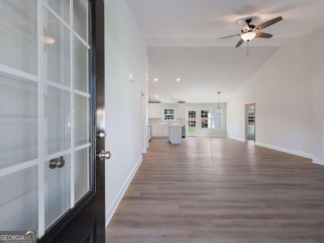 unfurnished living room with baseboards, recessed lighting, ceiling fan, lofted ceiling, and wood finished floors