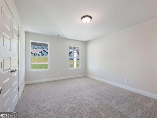 carpeted spare room featuring baseboards and visible vents