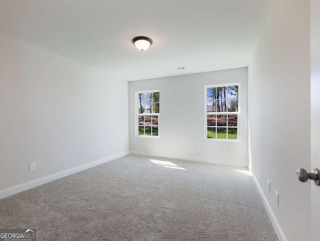carpeted empty room featuring visible vents, a wealth of natural light, and baseboards