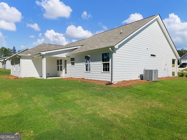 back of property featuring central air condition unit and a yard