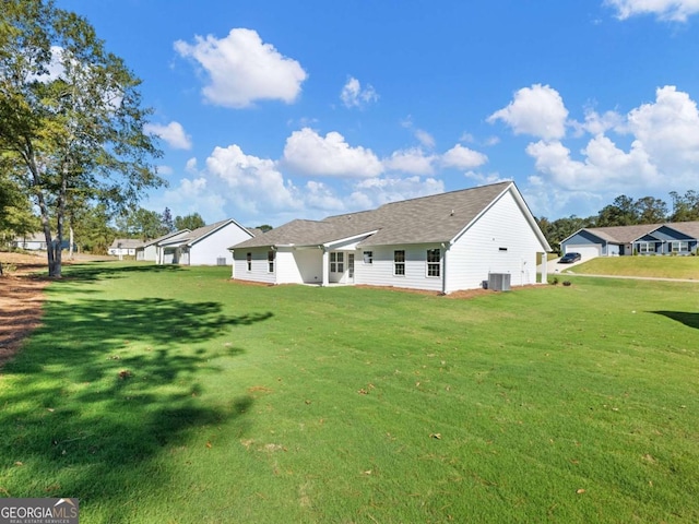 rear view of house featuring roof with shingles, cooling unit, and a lawn