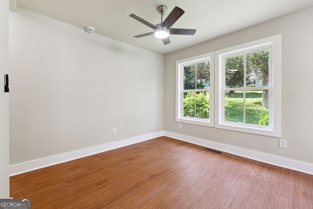 unfurnished room featuring wood finished floors, ceiling fan, baseboards, and visible vents