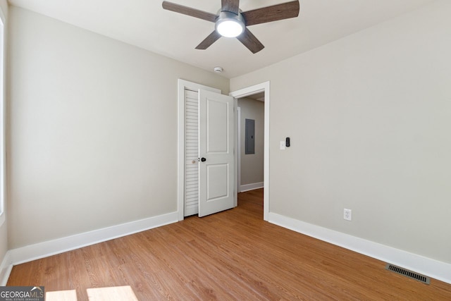 unfurnished bedroom with light wood-type flooring, baseboards, a closet, electric panel, and visible vents