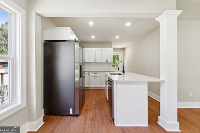 kitchen featuring stainless steel appliances, white cabinets, light wood-type flooring, and a sink