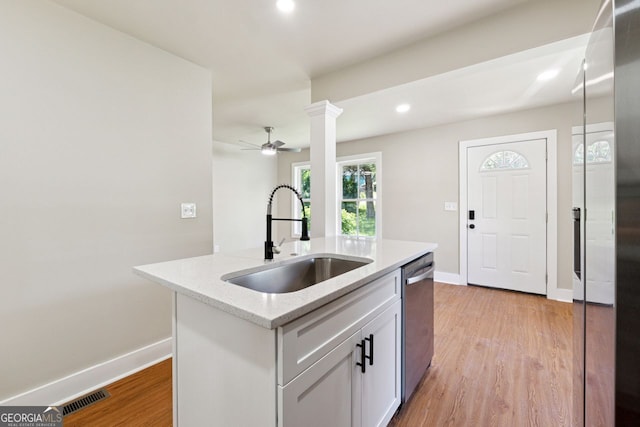 kitchen with visible vents, stainless steel dishwasher, a sink, and baseboards