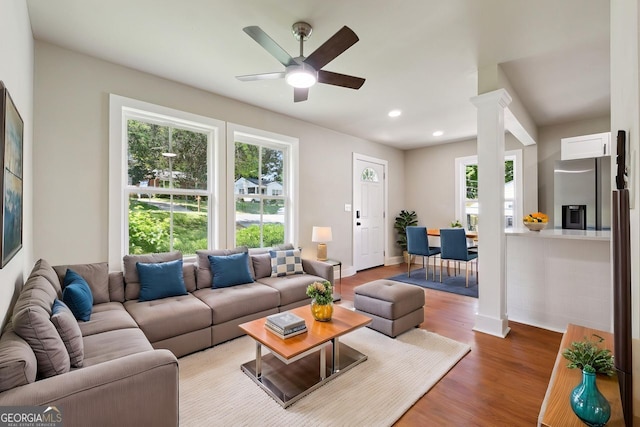 living area featuring wood finished floors, baseboards, a ceiling fan, and plenty of natural light