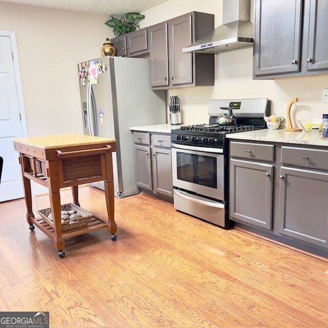 33 Mountain View Dr, Rockmart, GA 30153 - kitchen featuring wall chimney exhaust hood, stainless steel gas range oven, gray cabinets, light wood-type flooring, and white refrigerator with ice dispenser