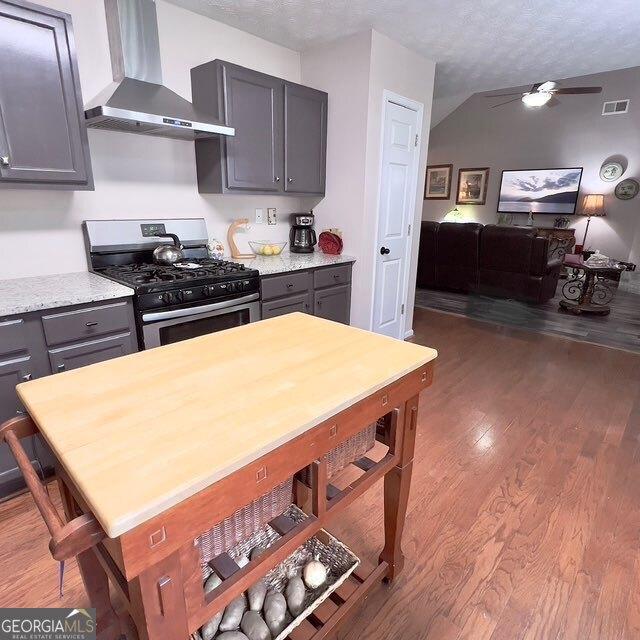 33 Mountain View Dr, Rockmart, GA 30153 - kitchen with wall chimney range hood, stainless steel gas range oven, wood finished floors, a ceiling fan, and a textured ceiling
