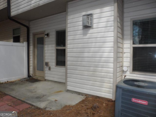 entrance to property featuring central AC unit, fence, and a patio area