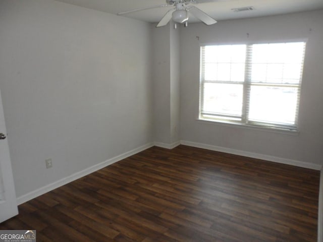 empty room featuring dark wood-style flooring, baseboards, a ceiling fan, and visible vents