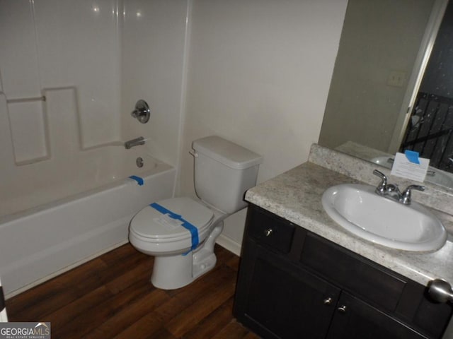 full bath with toilet, wood finished floors, vanity, and tub / shower combination