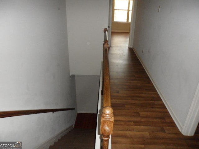 hallway with baseboards, an upstairs landing, and wood finished floors