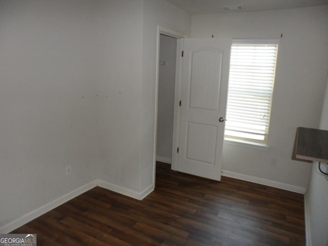 empty room featuring baseboards and dark wood finished floors