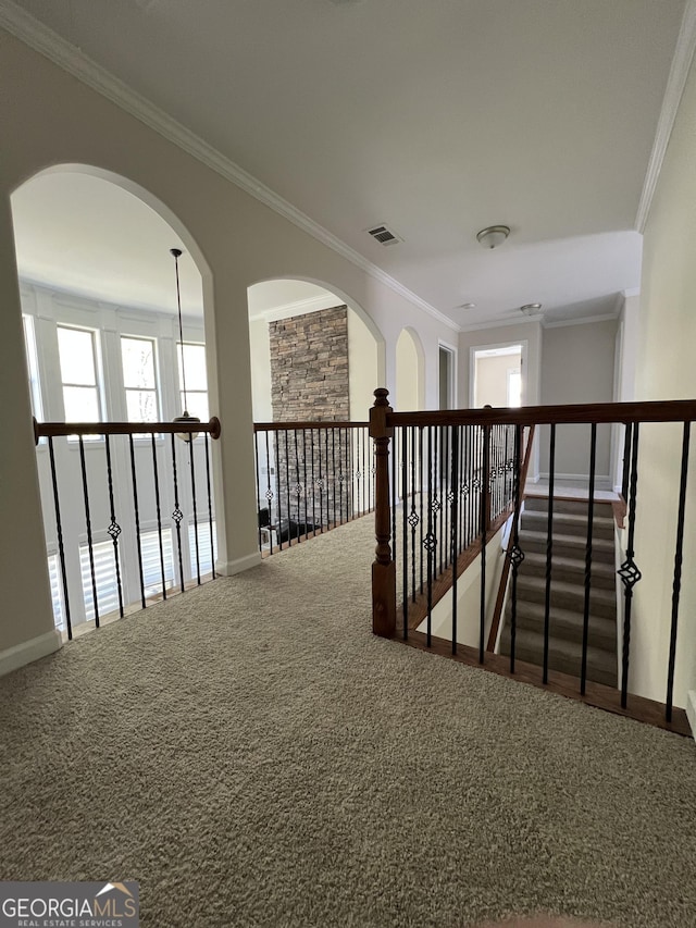 hallway featuring visible vents, baseboards, carpet floors, and crown molding